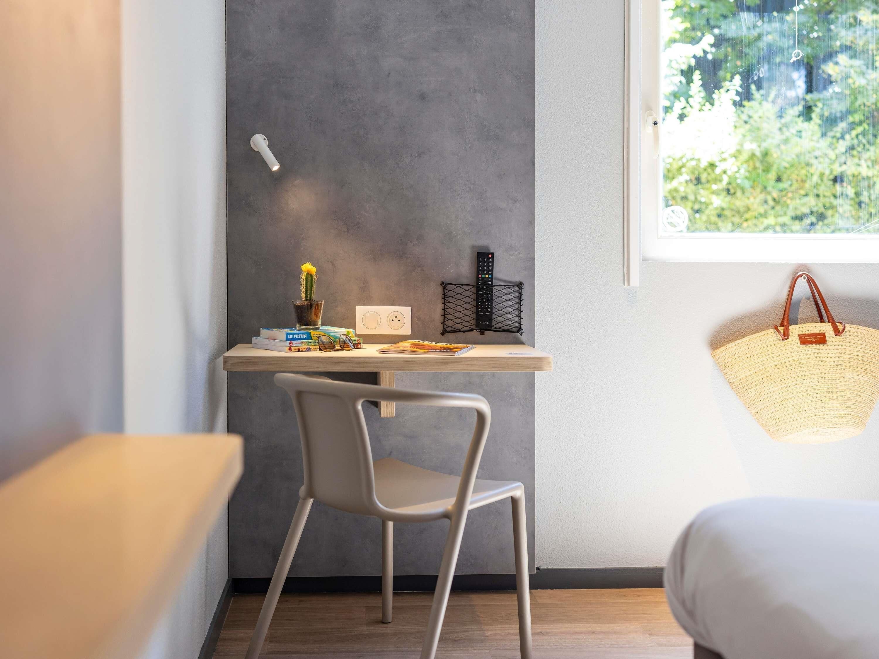 A modern room with a desk, chair, and a window with a view of greenery.