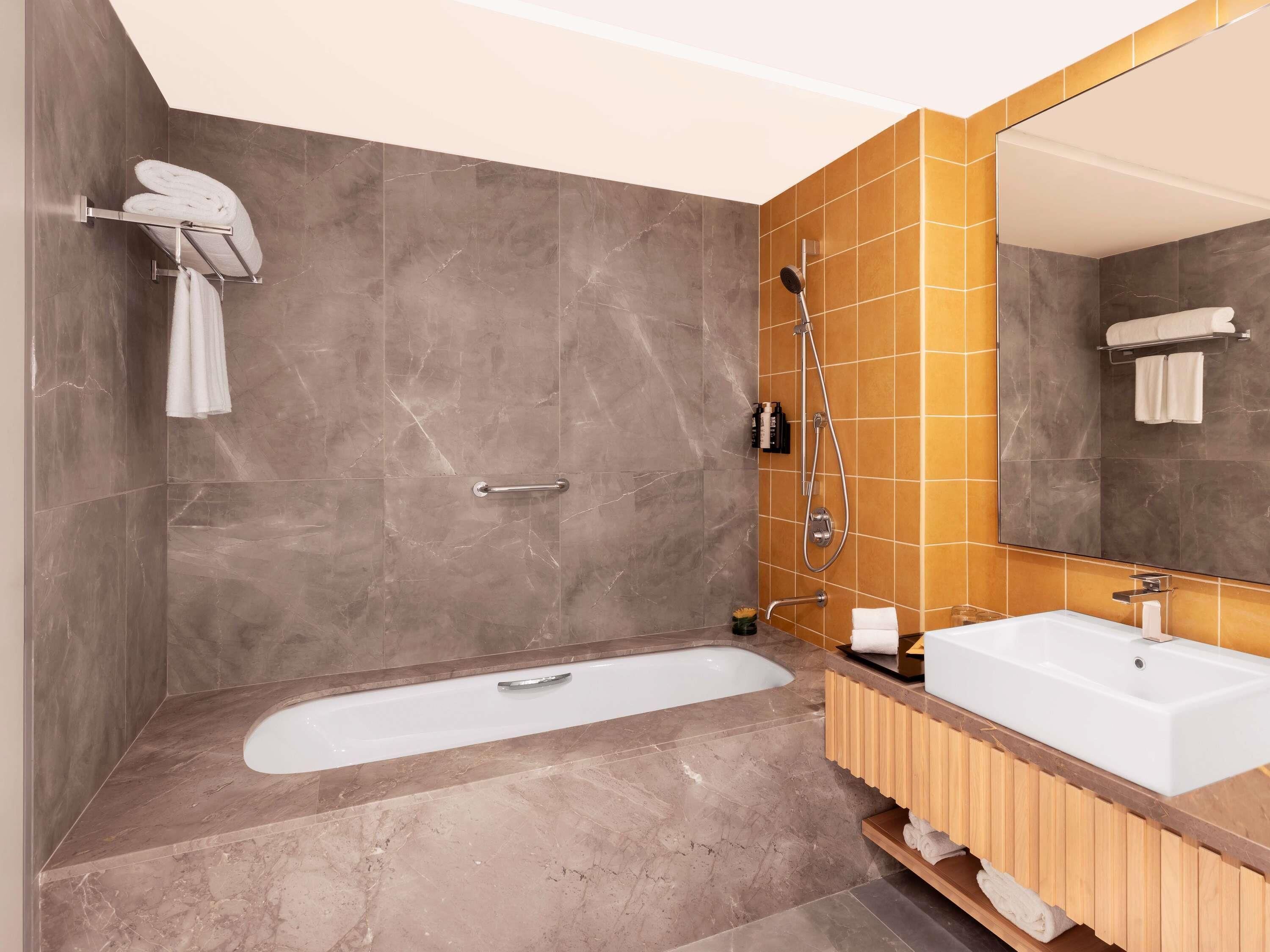 A modern bathroom with a bathtub, a sink, a shower, and a large mirror.