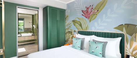 Habitación de hotel con cama, mesita de noche, armario verde y baño con espejo, además de un mural floral en la pared.