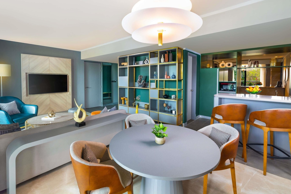 A modern living room with a round table, sofas, and a built-in bookshelf.