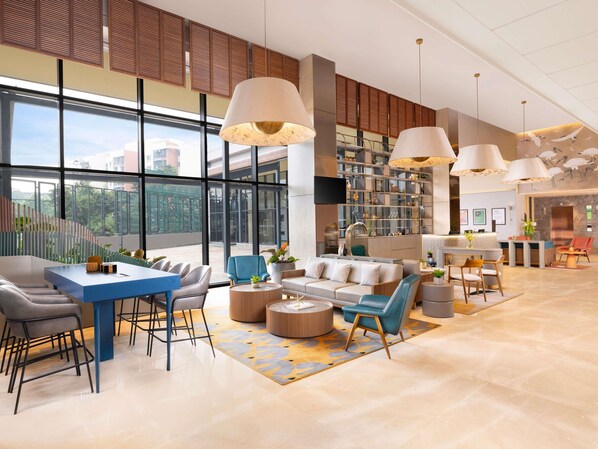 A spacious lobby with a reception desk, seating area, and a large window offering a view of the outdoors.