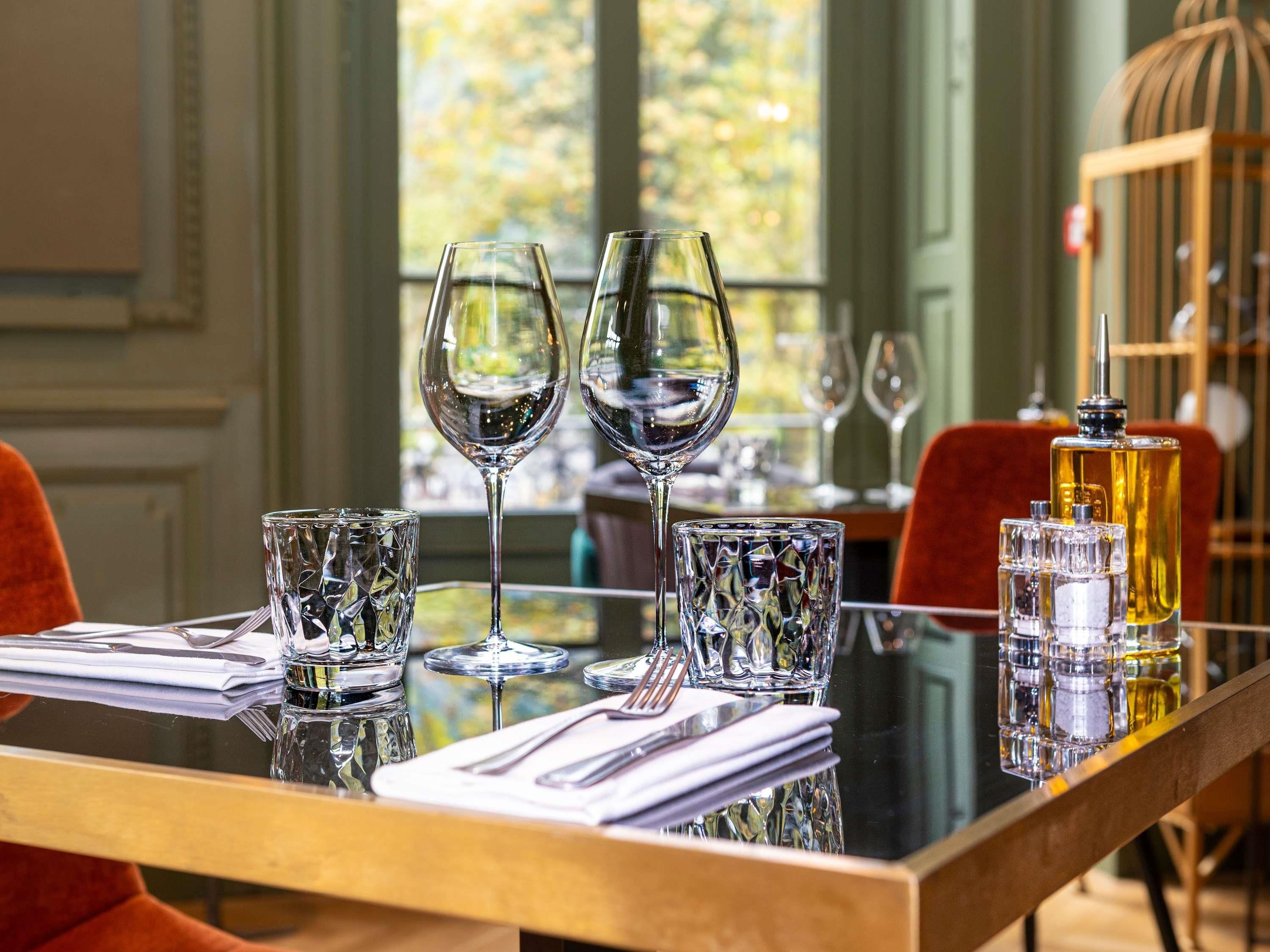 A dining table set with two wine glasses, a bottle of perfume, and a glass of water.