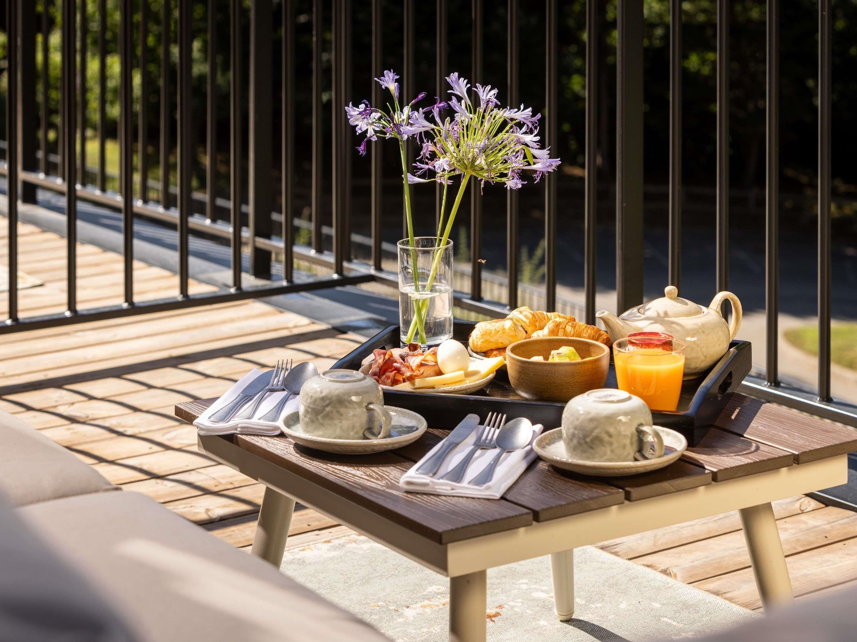 A breakfast setup on an outdoor table with a metal railing in the background.