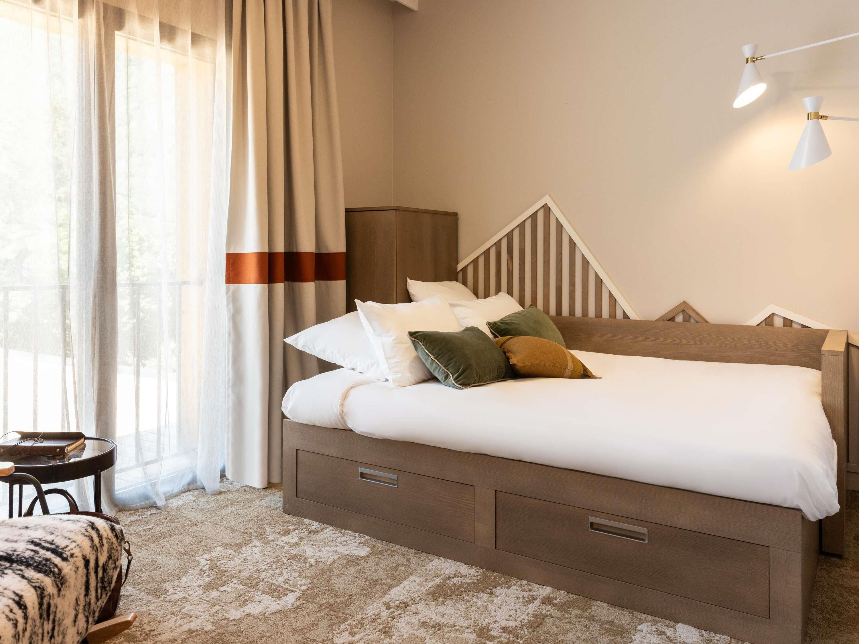 A neatly made bed with pillows, a bedside table, and a lamp.