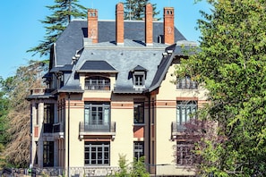 A multi-story building with a symmetrical facade, multiple chimneys, and a balcony with a wrought iron railing. - Mercure Ax Les Thermes (Ax-les-Thermes)