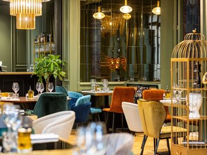 A restaurant interior with tables set for dining, chairs, hanging lights, and a large window. - Mercure Ax Les Thermes (Ax-les-Thermes)