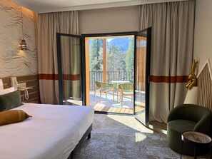 A hotel room with a bed, a chair, a table, and a balcony with a view of trees and mountains. - Mercure Ax Les Thermes (Ax-les-Thermes)
