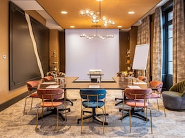 Une salle de conférence équipée d’une grande table, de chaises, d’un projecteur et d’un tableau blanc.
