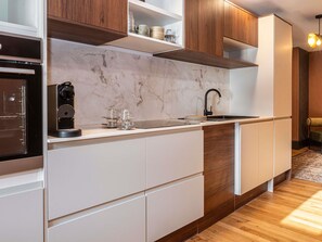 Una cocina moderna con armarios blancos, salpicadero de mármol y horno empotrado.