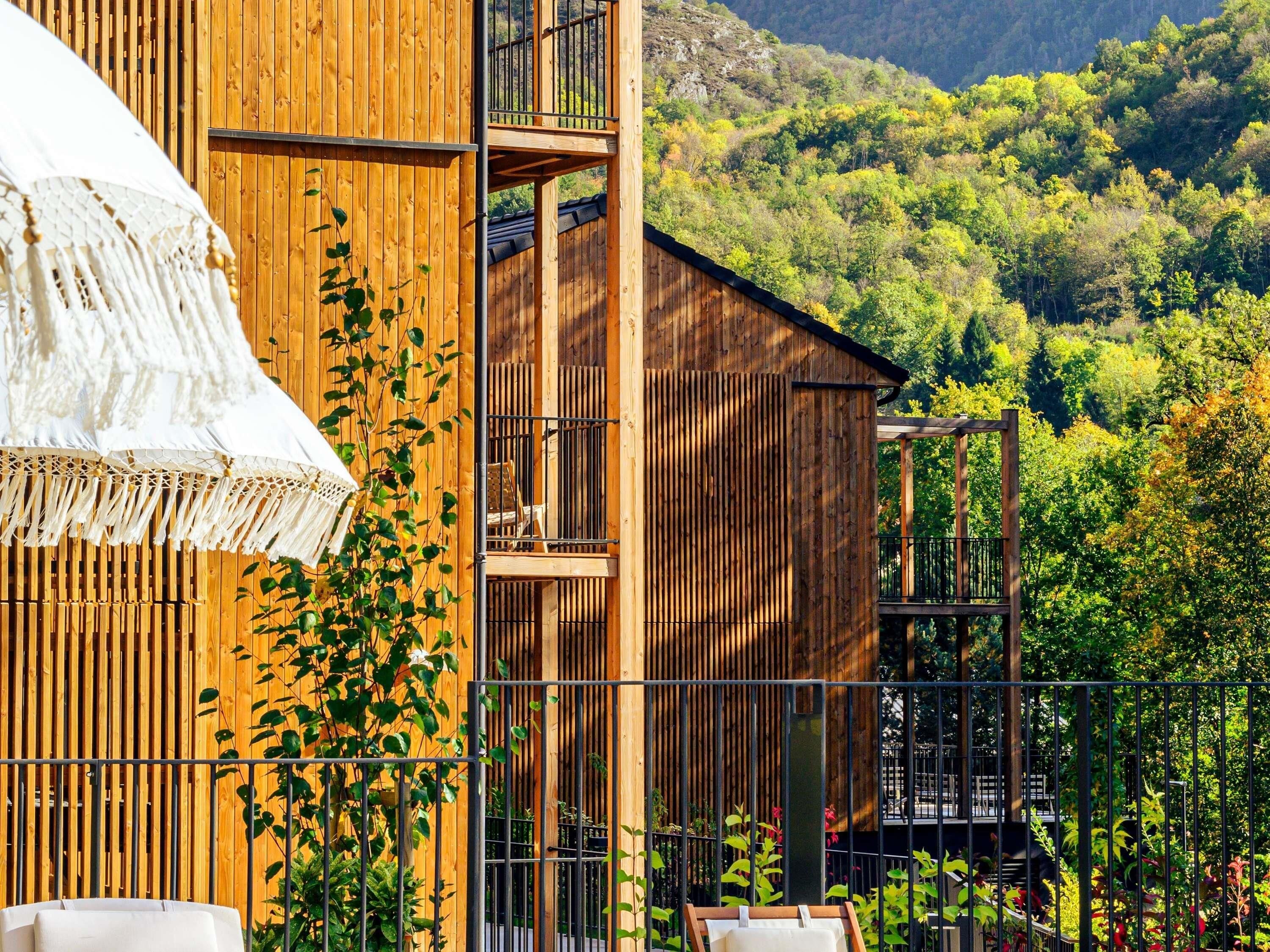 A wooden building with a balcony and a view of a forested hillside.