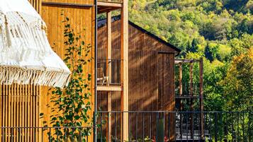A wooden building with a balcony and a view of a forested hillside.