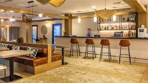 Zona de bar con asientos, barra y una variedad de botellas.