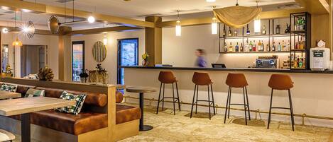 A bar area with seating, a bar counter, and a variety of bottles.