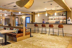 A bar area with seating, a bar counter, and a variety of bottles. - Mercure Ax Les Thermes (Ax-les-Thermes)
