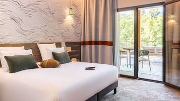 A hotel room with a large bed, a wooden headboard, a view of the outdoors through a glass door, and a textured wall.