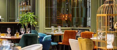 Een restaurantinterieur met gedekte tafels, stoelen, hangende lampen en een groot raam.