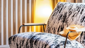Una sala de estar moderna con un sofá estampado, un adorno de pared y una lámpara.
