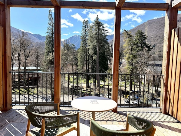 A wooden deck with two wicker chairs and a small table, overlooking a mountainous landscape with trees and a clear sky. - Mercure Ax Les Thermes (Ax-les-Thermes)