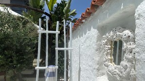 A white-walled building with a tiled roof, a white gate, and a window with a decorative frame. - Mina Otel by Adda Alaçatı (Cesme)