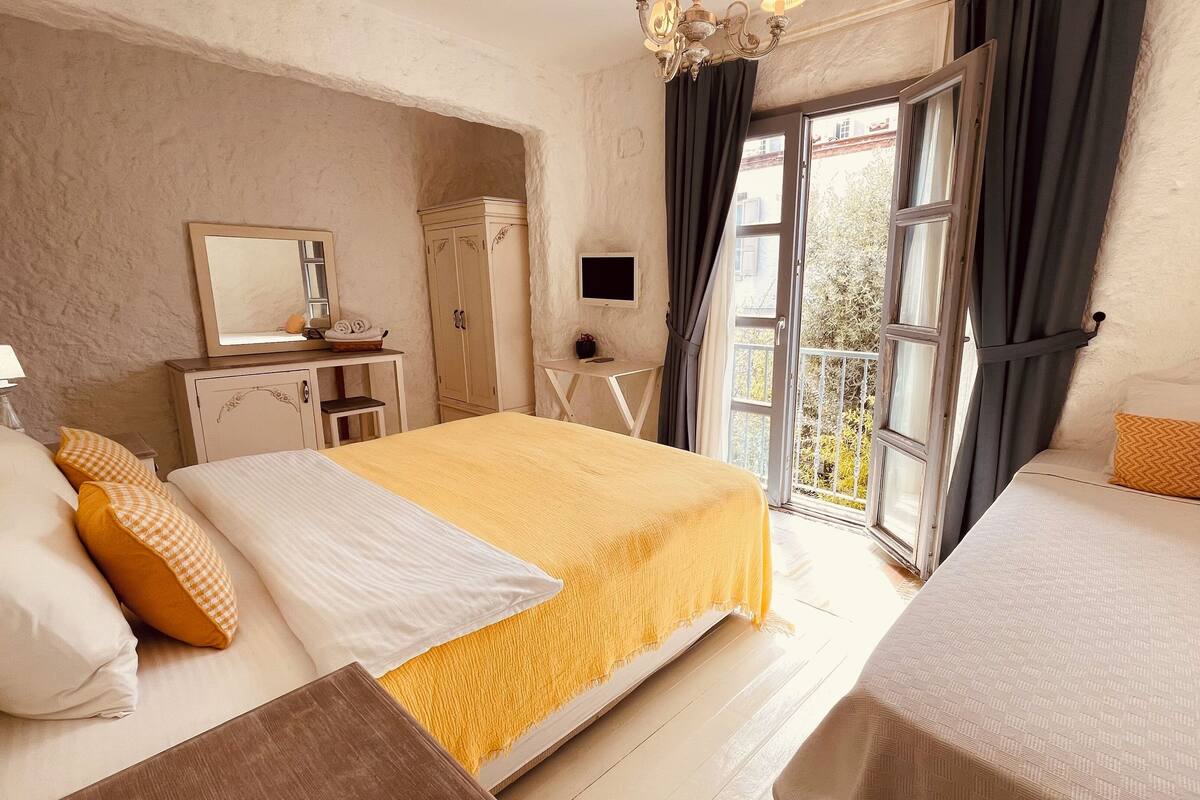 Un dormitorio con una cama grande, una cama más pequeña, un aparador, un espejo y una ventana con cortinas.