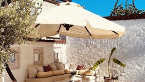 A poolside area with a white outdoor sofa, a table, and a potted plant. - Mina Otel by Adda Alaçatı (Cesme)
