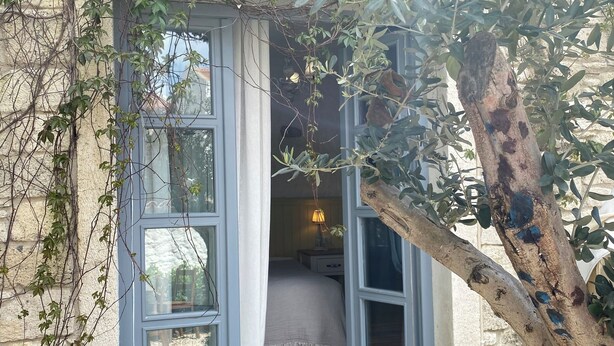 A room with a bed, a nightstand, a lamp, and a view through a window with curtains. - Mina Otel by Adda Alaçatı (Cesme)