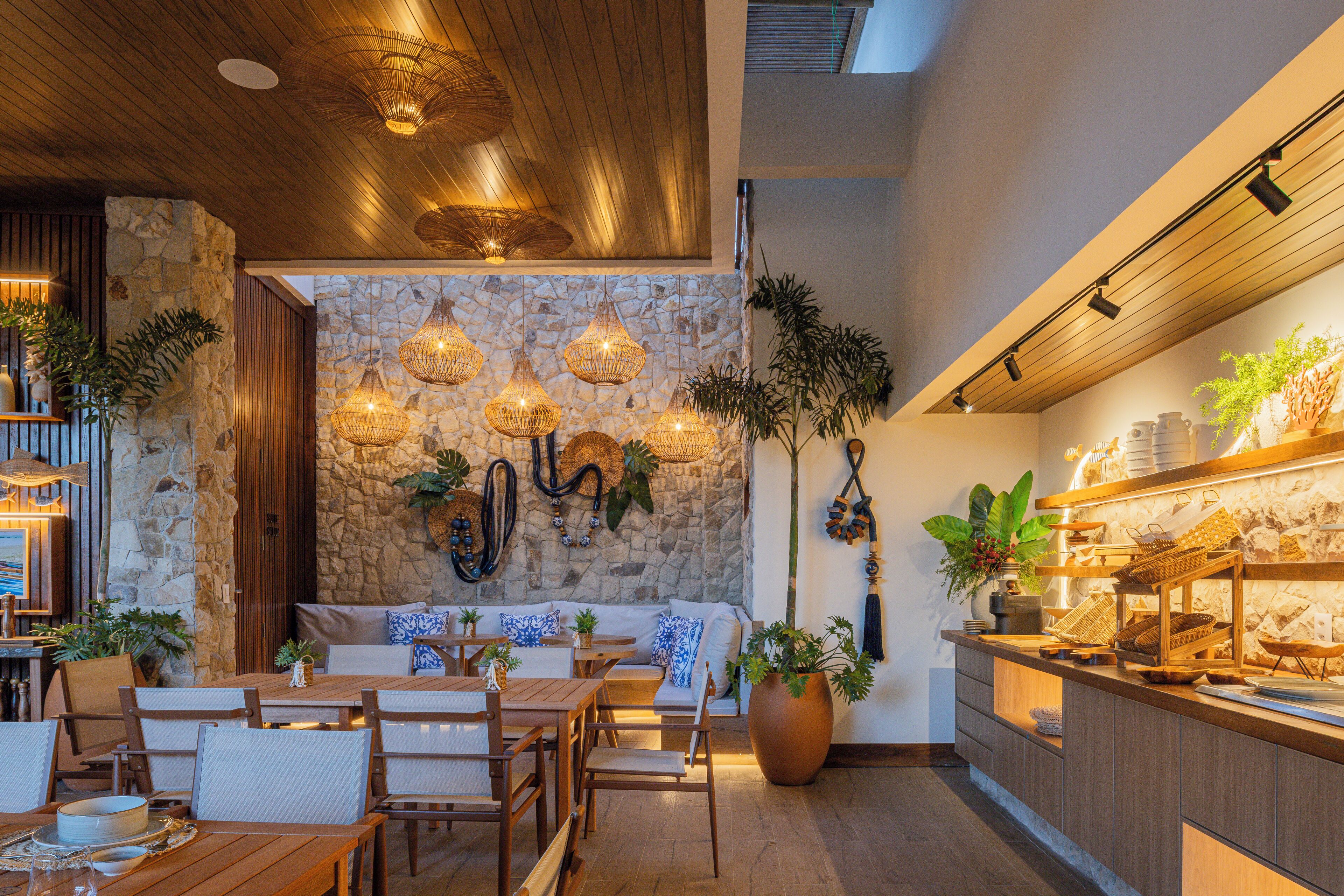 Un restaurant chaleureux, avec des meubles en bois, des murs en pierre et des luminaires suspendus.