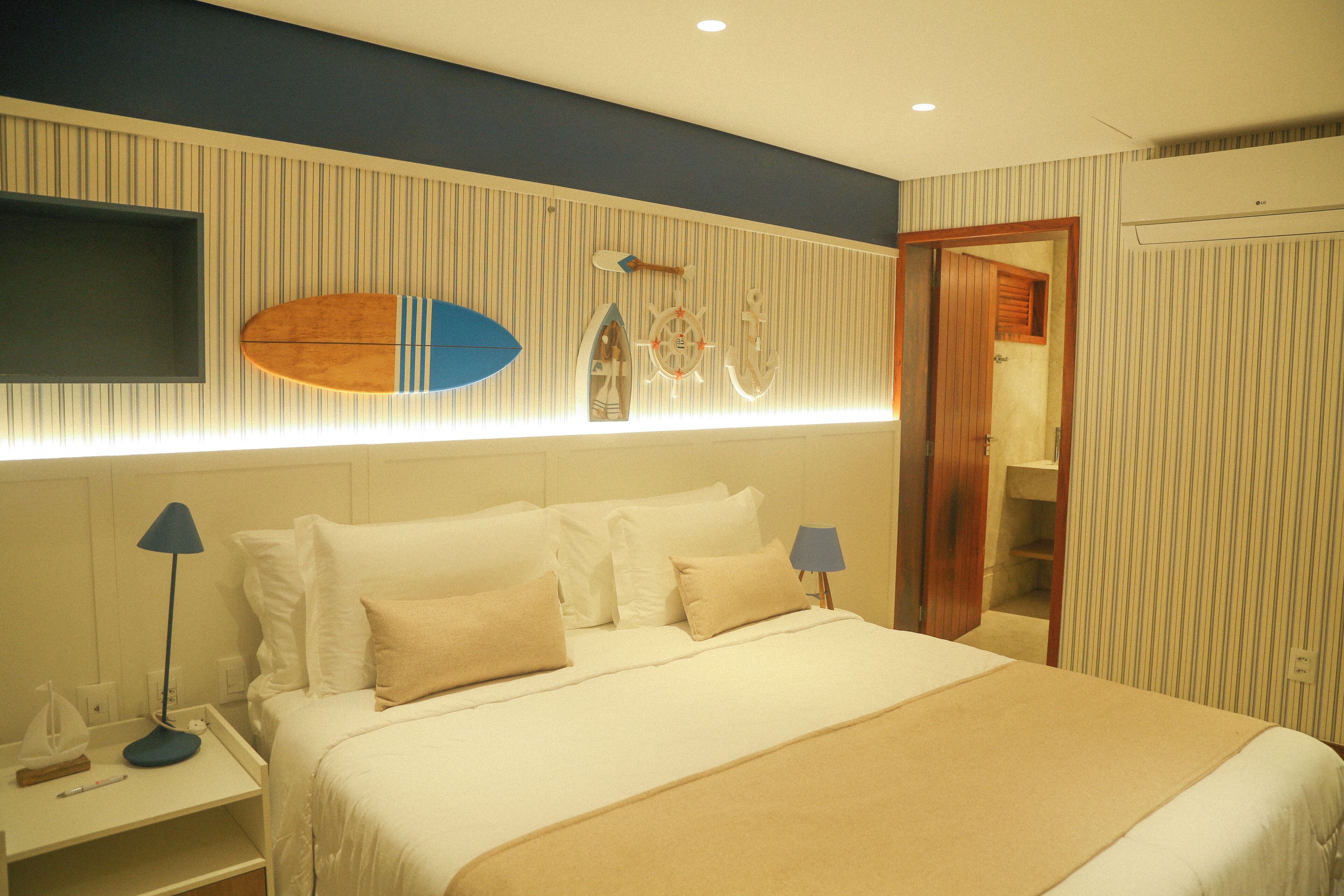 Habitación de hotel con cama, mesitas de noche, televisor montado en la pared y puerta que da a un armario.