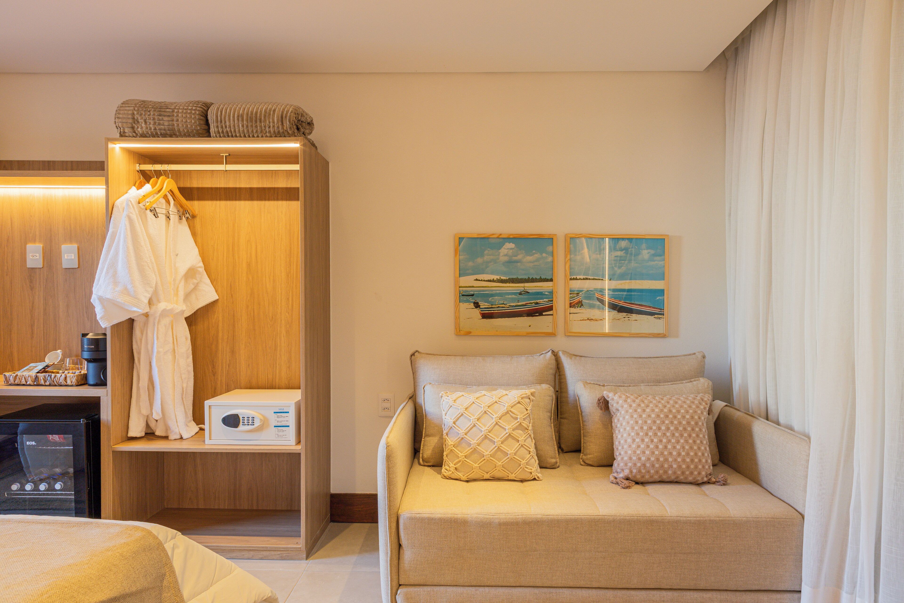 Una habitación de hotel con una cama, un sofá, un armario y obras de arte en la pared.