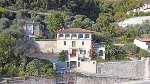 A hillside villa with a stone facade, multiple balconies, and a lush garden. - Your Breathtaking Penthouse (Gargnano)