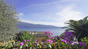 A coastal view with a building, a mountain, and a body of water. - Your Breathtaking Penthouse (Gargnano)