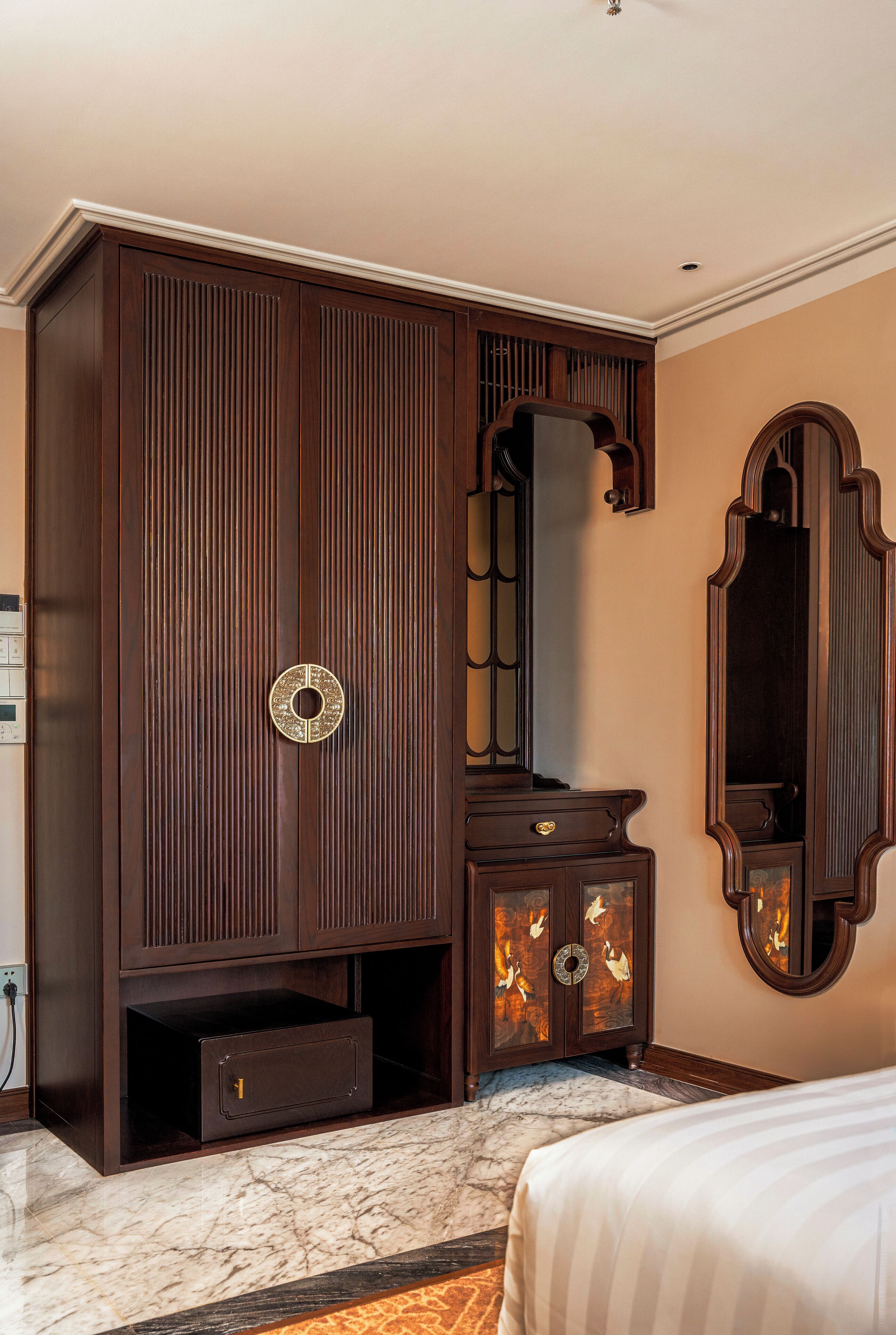 Une chambre à coucher avec une grande armoire, une commode et un miroir.