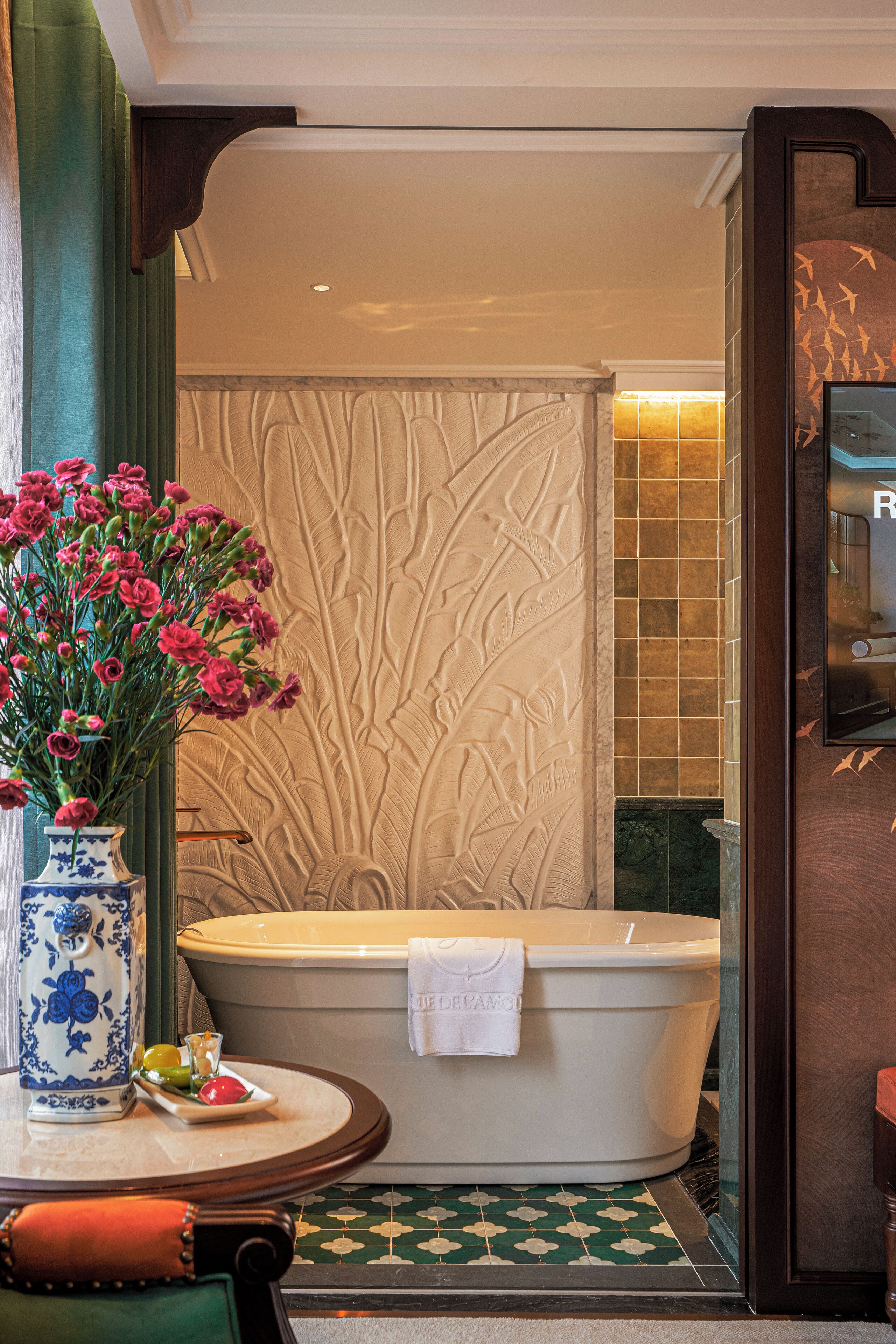 Une salle de bain avec une baignoire sur pieds, un vase de fleurs et un sol carrelé.