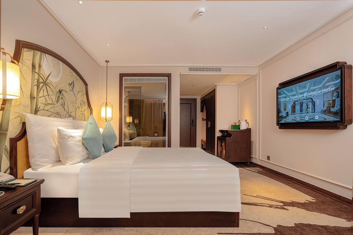 A hotel room with a large bed, bedside lamps, a flat-screen TV, and a mirror.
