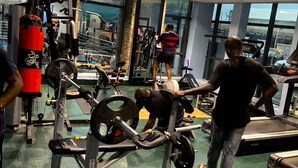 Et fitnesscenter med forskellig træningsudstyr, store vinduer og et højt til loftet.