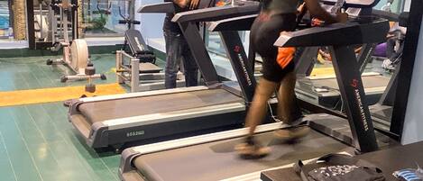 A gym with treadmills, weight machines, and a person using a treadmill.