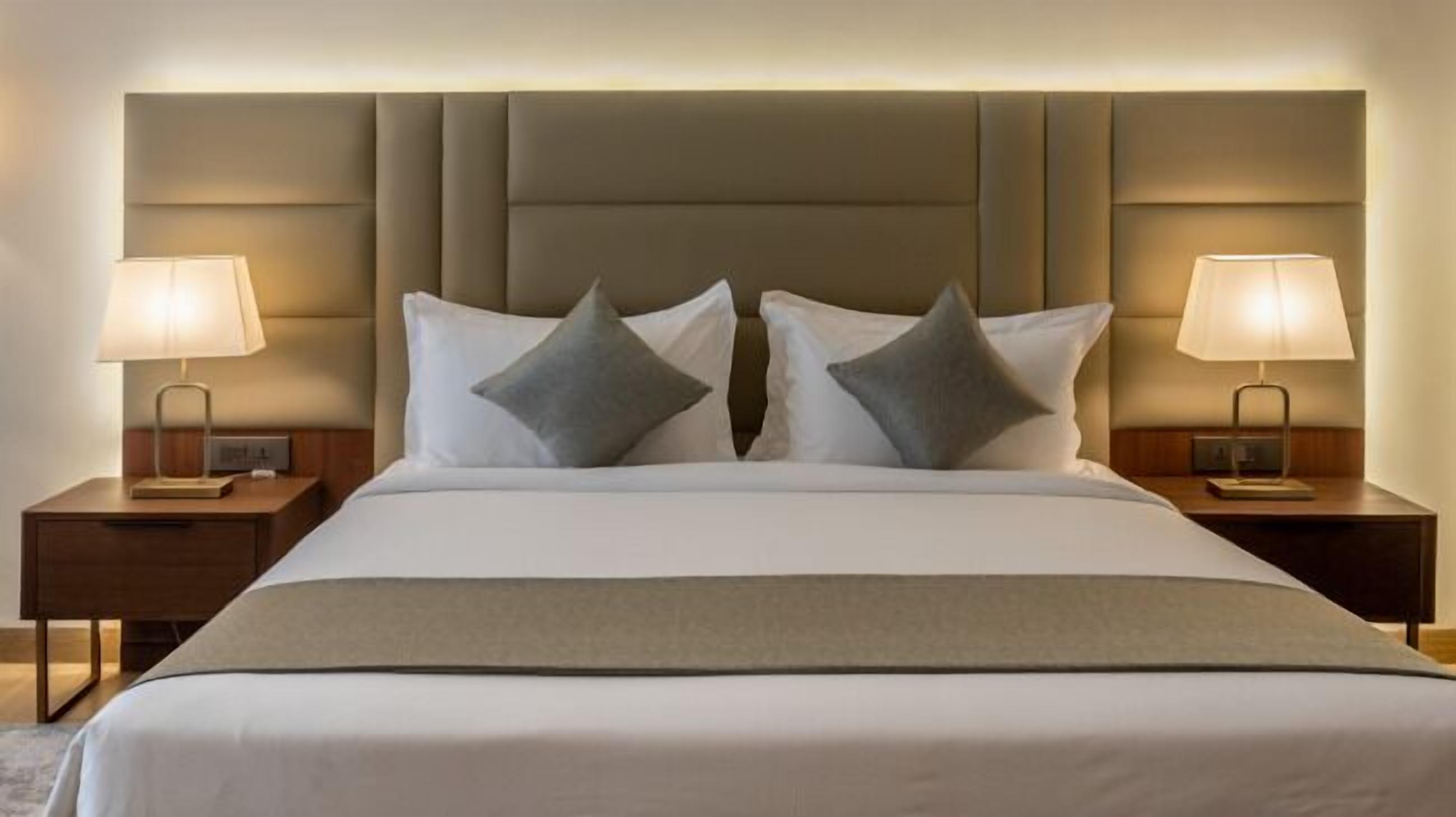 A hotel room with a large bed, two bedside tables with lamps, and a padded headboard.