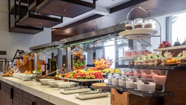 A buffet with various food items and beverages, including fruits, pastries, and desserts.