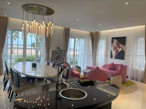 A modern dining area with a round table, chairs, and a central light fixture.