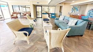A spacious lobby with wicker furniture, a blue sofa, and a coffee table. - Aransas Bay Condo with Balcony, Pool & Lighted Pier (Rockport)