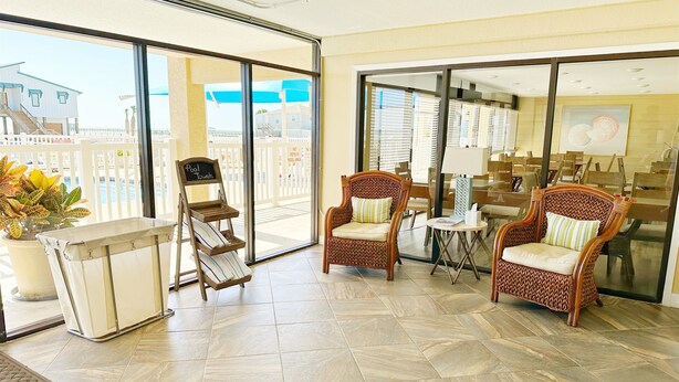 A spacious balcony with a poolside chair, a towel rack, and a view of the beach and buildings. - Aransas Bay Condo with Balcony, Pool & Lighted Pier (Rockport)
