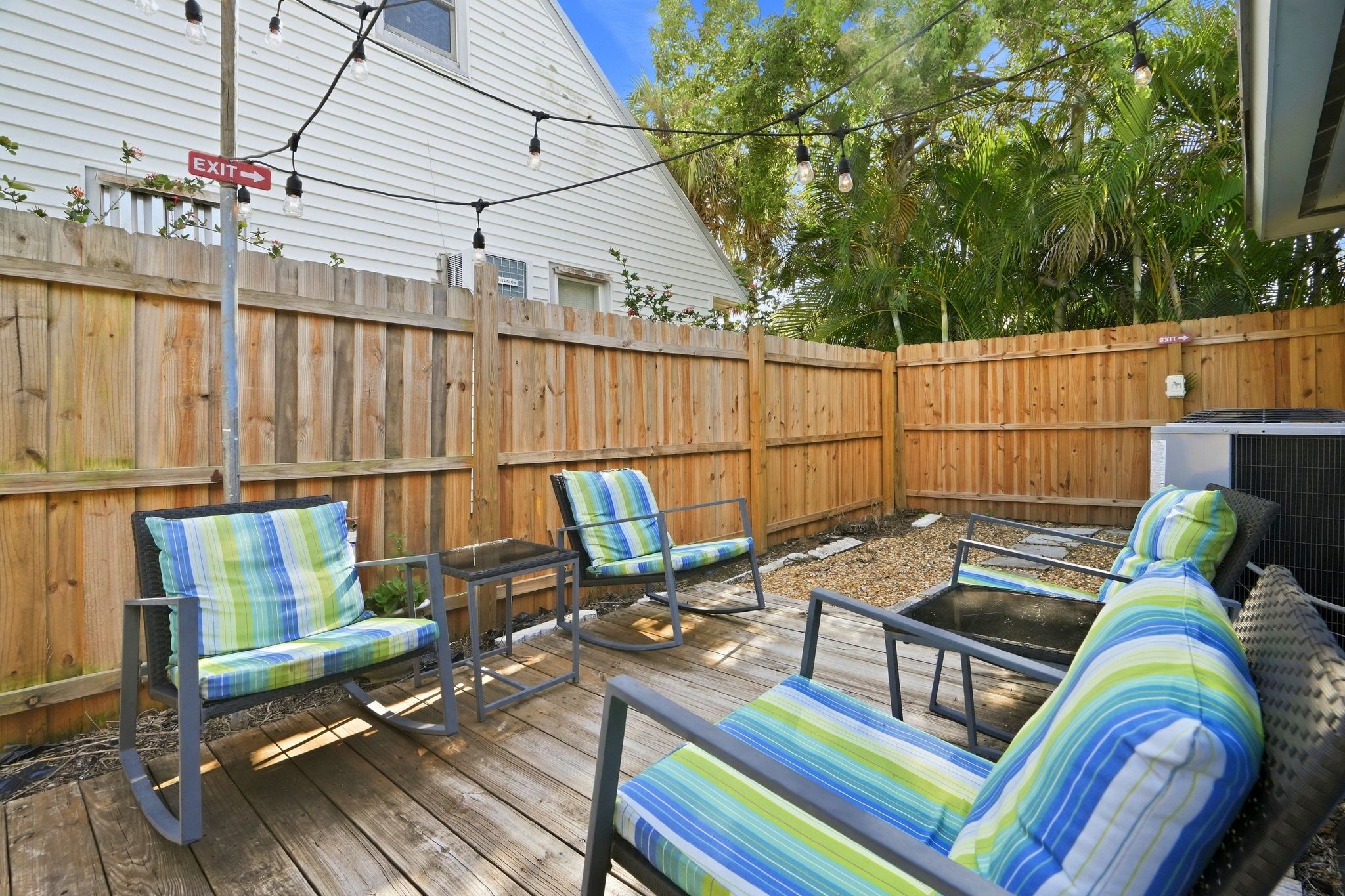 A wooden deck with outdoor furniture, including chairs and a table, and a wooden fence in the background.