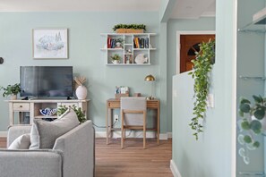 A living room with a TV, bookshelf, and a desk. - Dunedin Blue Bird Bungalow (Dunedin)