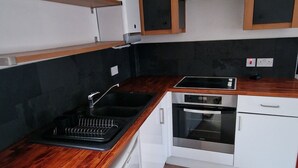 A compact kitchen with a wooden countertop, a built-in oven, and white cabinetry.