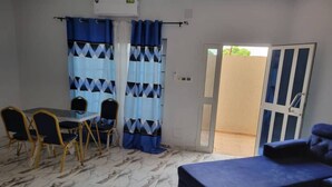 Quarto com cama, mesa e cadeiras, e vista para o exterior.