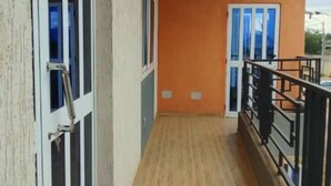 Een smal balkon met een houten vloer, een metalen hekwerk en een hangende lamp.