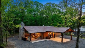 A rustic cabin with a stone chimney, wooden exterior, and a covered patio area.