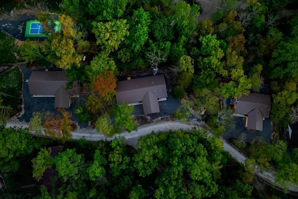 "Aerial View of Three Charming Cabins: Muskoka Loon, Muskoka Moose, and Muskoka Little Blue Penguin – With Pickleball Court and Playground."