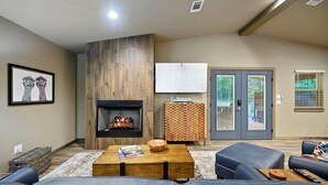 A modern living room with a fireplace, blue sofas, a wooden coffee table, and a large cabinet.