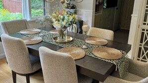 Un comedor con una mesa de madera oscura, sillas tapizadas en beige y una araña.